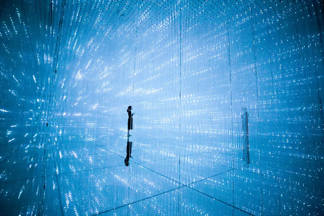 Blue crystal-light room with a mirrored floor at teamLab, the kind of installation covered by teamLab Tokyo tickets