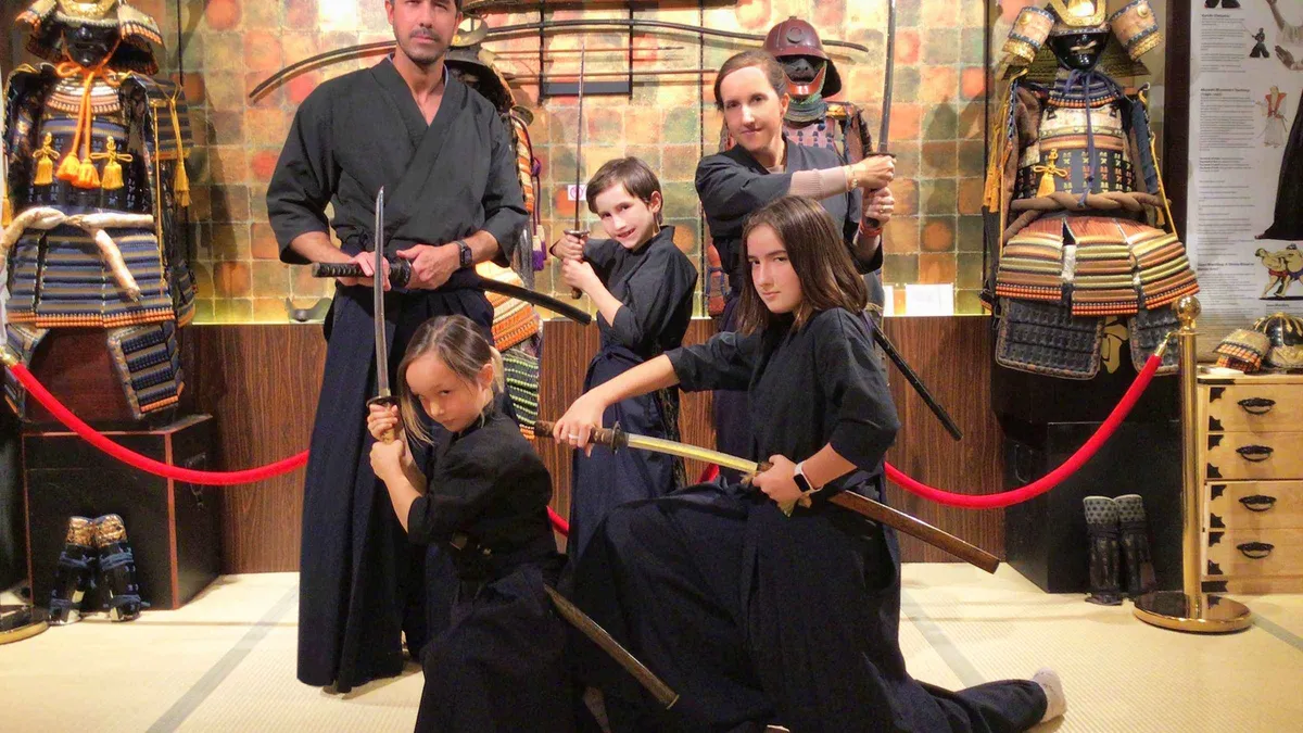 Family in samurai costume during a sword lesson at the Samurai Ninja Museum, a family-friendly museum in Tokyo